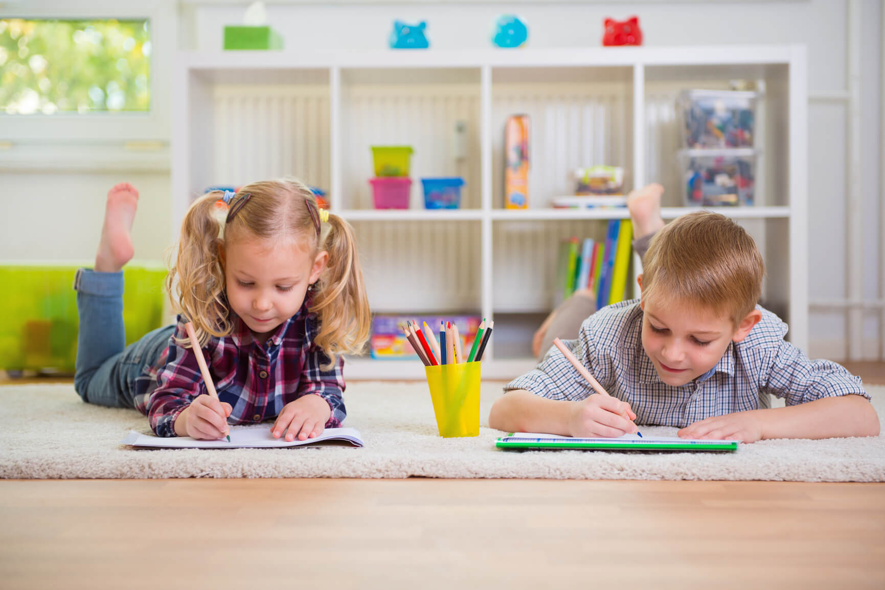 Two cute children draws on floor at home